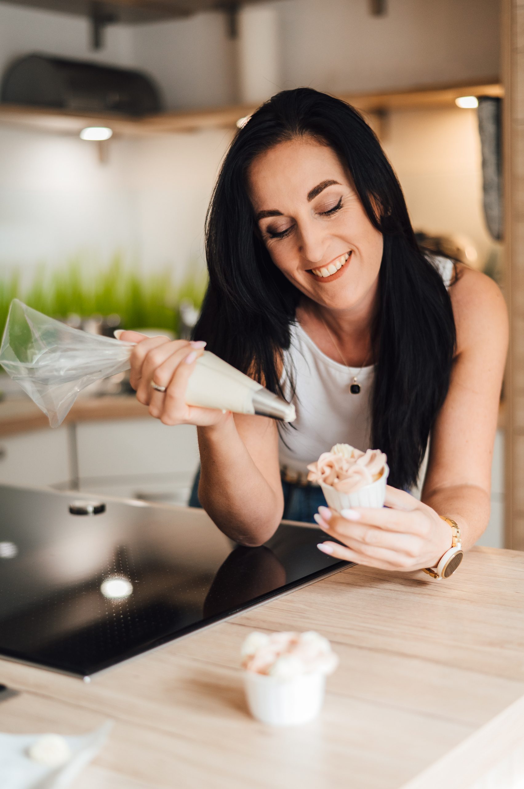 Backen lernen Sarah Sangermann verziert Cupcakes mit einer Spritztülle in ihrer modernen Küche
