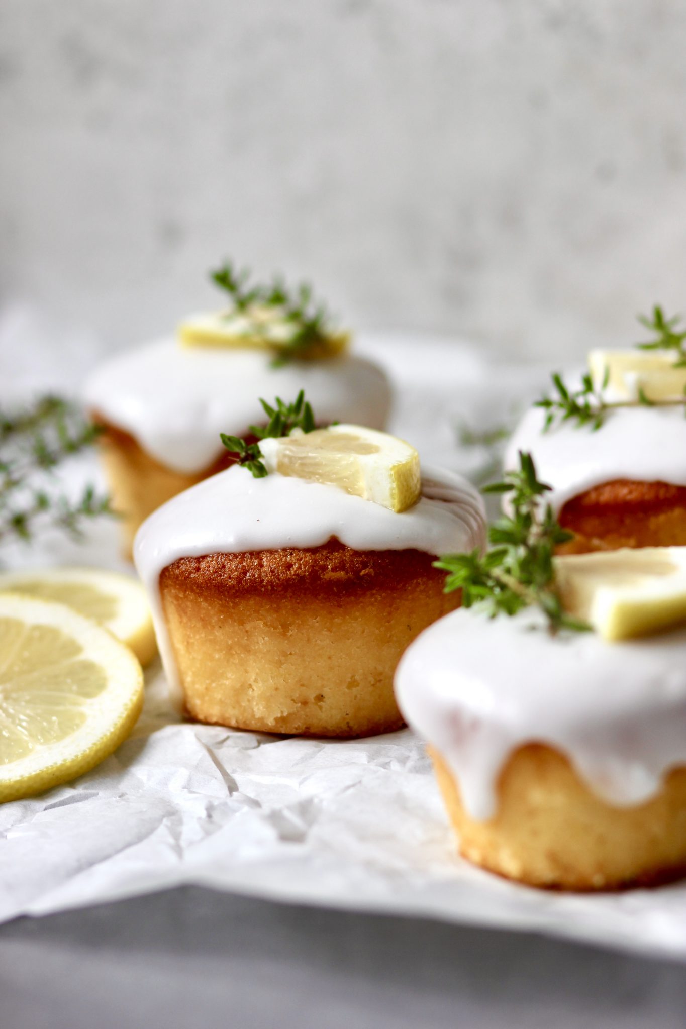 Zitronen-Thymian-Muffins mit Zuckerguss auf heller Servierplatte