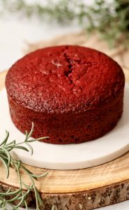 Red-Velvet-Tortenboden Red Velvet Tortenboden mit saftiger roter Krume auf weißem Teller, dekoriert mit Rosmarinzweigen