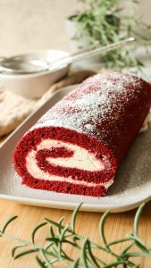 Red Velvet Biskuitrolle mit heller Cremefüllung, sauber aufgerollt und dekorativ angerichtet