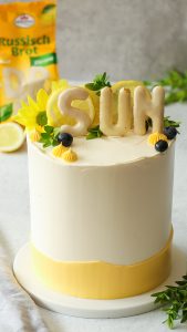 Zitronentorte mit Lemon Curd, Heidelbeeren und knusprigem Russisch-Brot-Crunch auf einer weißen Tortenplatte