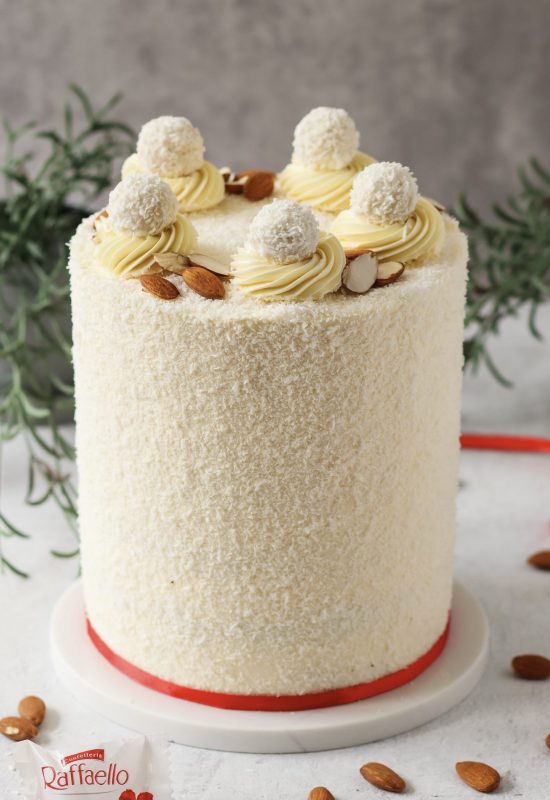 Hohe Raffaello Torte mit Kokosraspeln und Raffaello Pralinen auf einer Tortenplatte