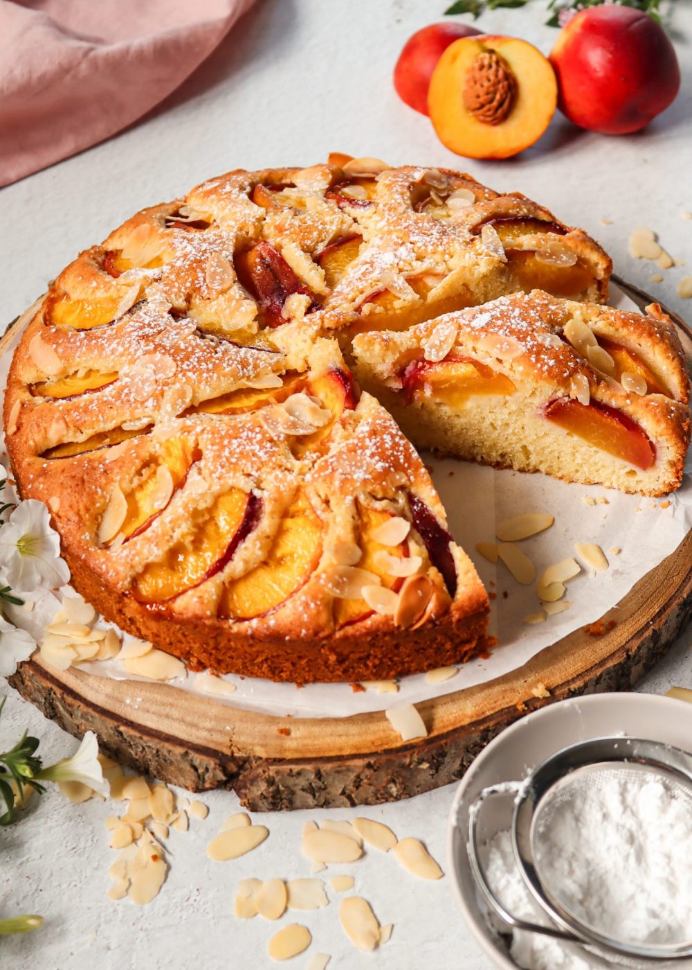 Angeschnittener Nektarinenkuchen mit saftigen Fr&uuml;chten und Mandelbl&auml;ttchen