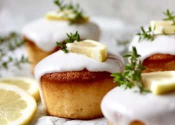 Zitronen-Thymian-Muffins mit Zuckerguss auf heller Servierplatte