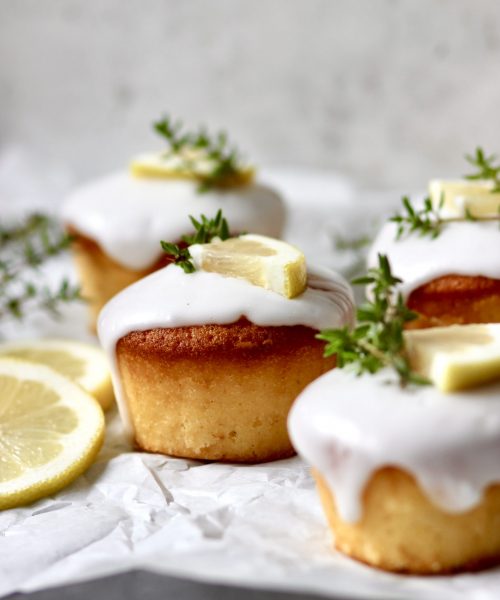 Zitronen-Thymian-Muffins mit Zuckerguss auf heller Servierplatte