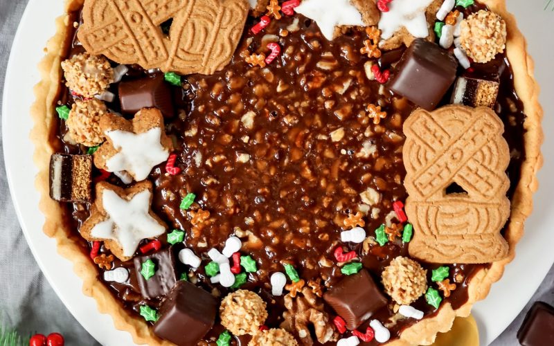 Schokoladen-Walnuss-Tarte mit M&uuml;rbeteigboden, Schokokaramellf&uuml;llung und winterlicher Dekoration aus Keksen, Pralinen und N&uuml;ssen.