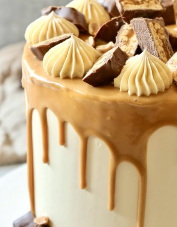 Hohe Snickers Drip Cake mit Karamell und Snickers-St&uuml;cken als Dekoration