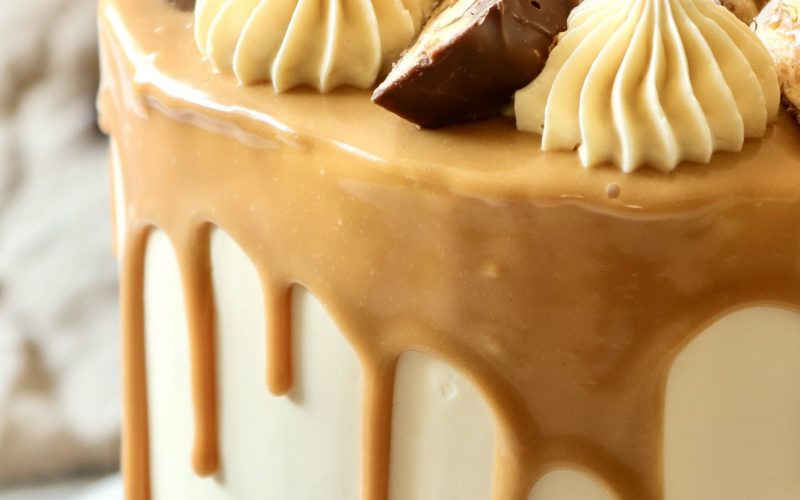 Hohe Snickers Drip Cake mit Karamell und Snickers-St&uuml;cken als Dekoration