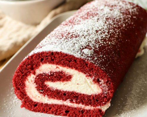 Red Velvet Biskuitrolle mit cremiger Füllung Red Velvet Biskuitrolle mit heller Cremefüllung, sauber aufgerollt und dekorativ angerichtet