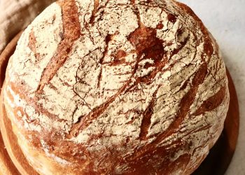 Frisch gebackenes Wei&szlig;brot mit rustikaler Kruste aus dem R&ouml;mertopf auf einem Holzbrett