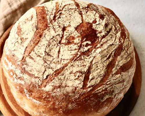 Weißbrot aus dem Römertopf Frisch gebackenes Weißbrot mit rustikaler Kruste aus dem Römertopf auf einem Holzbrett