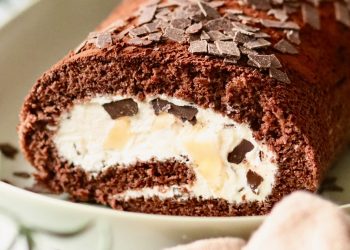 Banana Split Biskuitrolle mit Sahne, Banane und Schokostückchen angeschnitten Banana Split Biskuitrolle mit Sahne, Banane und Schokoraspeln angeschnitten