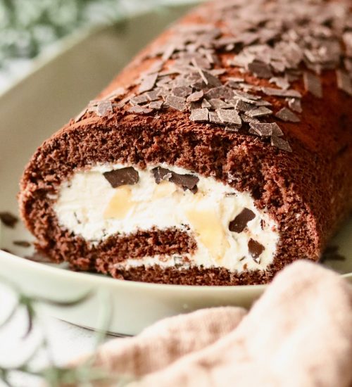 Banana Split Biskuitrolle mit Sahne, Banane und Schokoraspeln angeschnitten