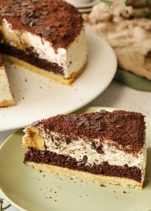 Banana Split Torte angeschnitten auf Teller &ndash; mit Banane, Sahne und Schokolade