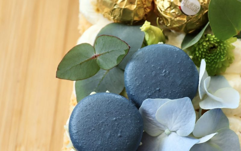 Detailaufnahme eines Number Cakes mit Vanillecreme, blauen Macarons und floraler Dekoration